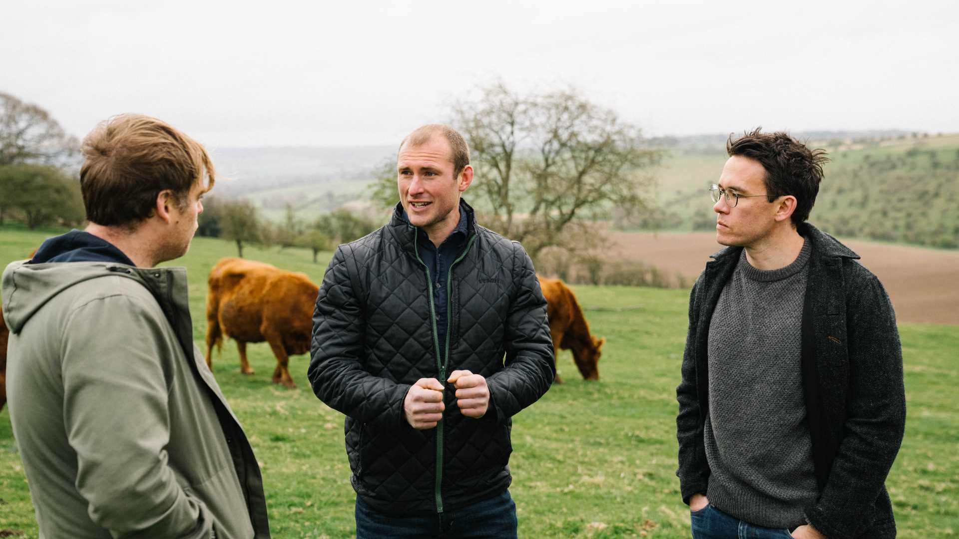 Phil and To, co founders of Honest Burgers stand in a field with a Grassroots farmer