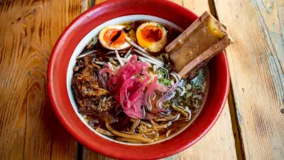 This is a photo of the Bone Daddies and Black Bear collaboration, which includes Bone Daddies beef bone broth, Black Bear beer braised brisket, bone marrow, pink pickled onions, bamboo shoots, beansprouts and a soy Clarence Court egg.